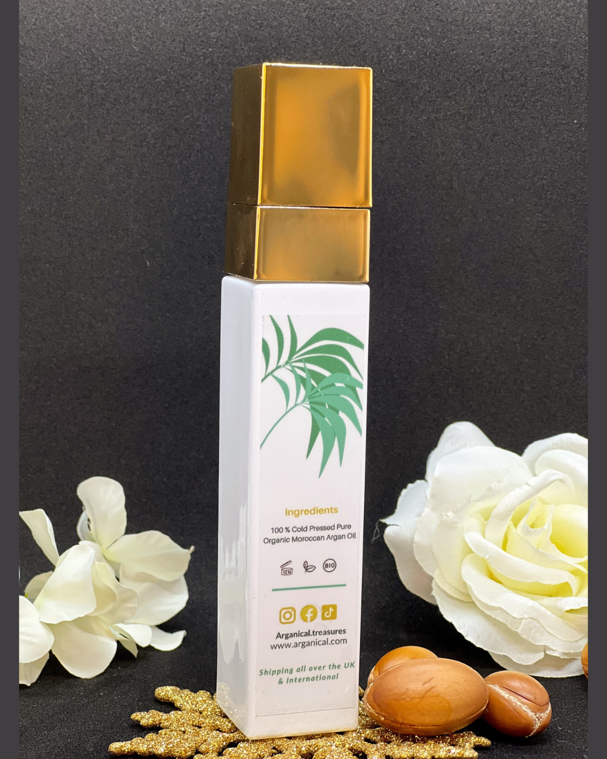 Back of Arganical argan oil 50ml bottle with gold cap on a dark background with argan nuts.